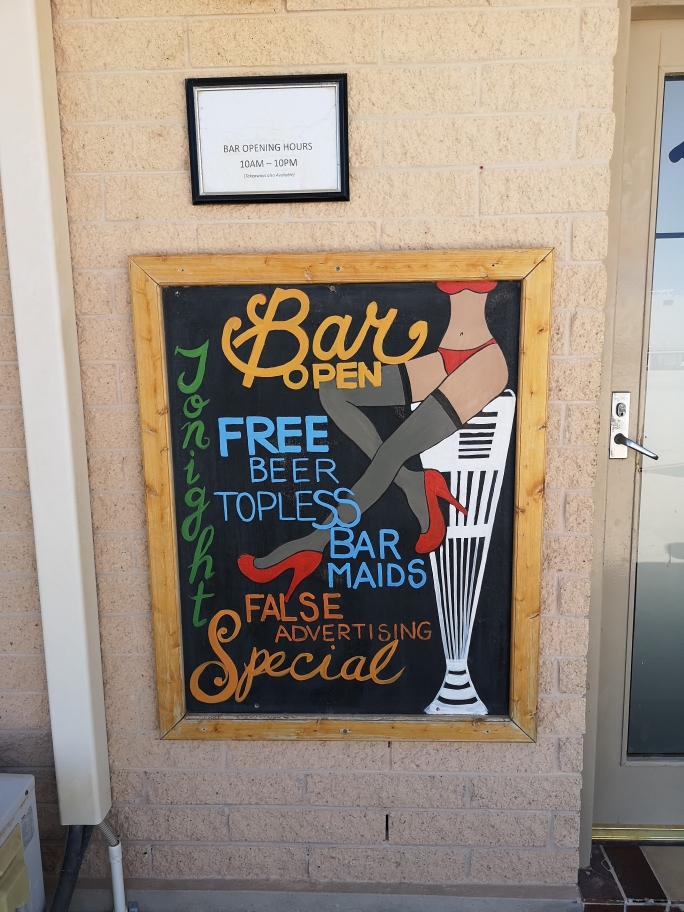 Le bar de la Nullarbor Roadhouse. Il indique "Bières gratuites, serveuses aux seins nus et publicités mensongères"